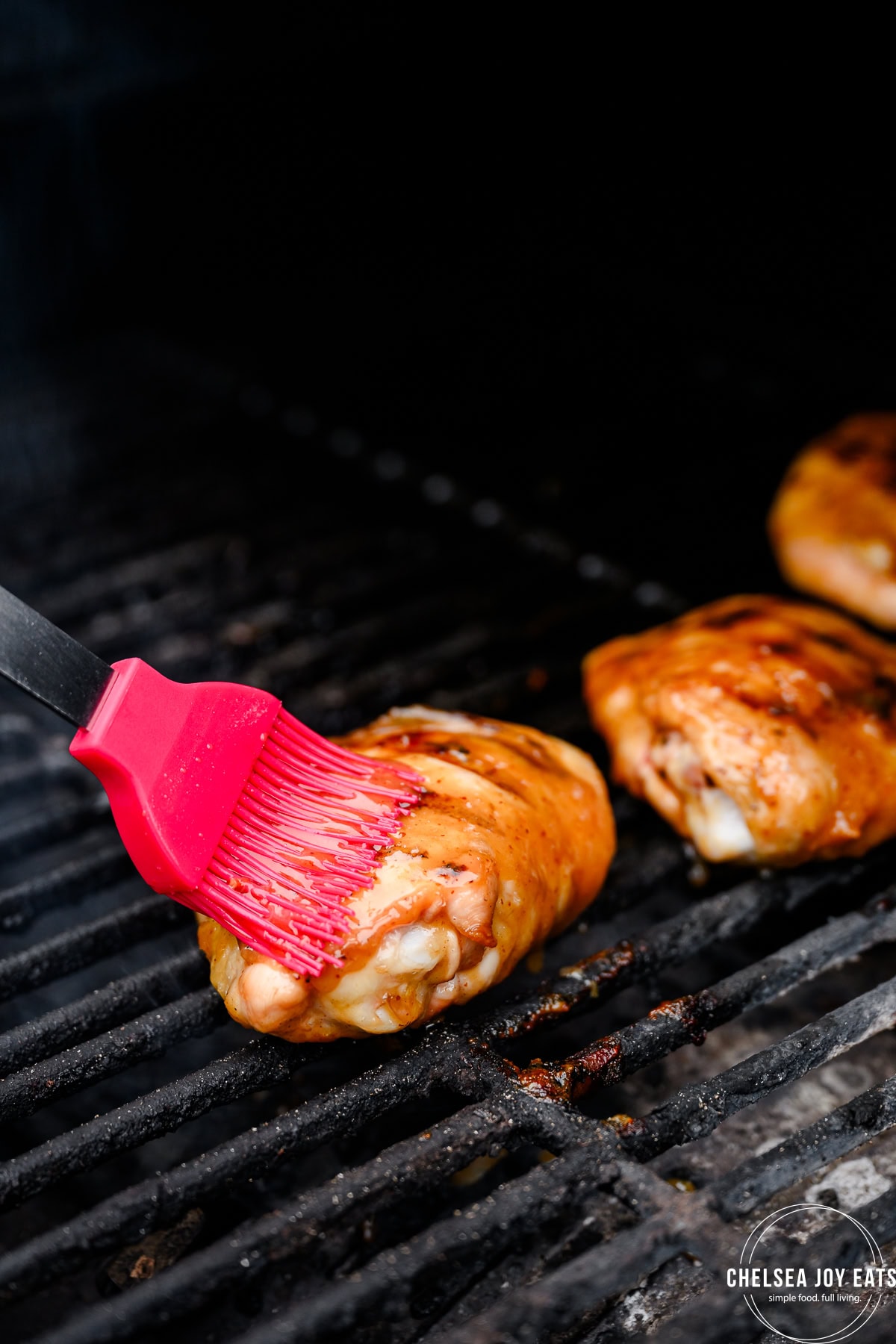Silicon brush basting grilled chicken thighs with a maple Dijon sauce.