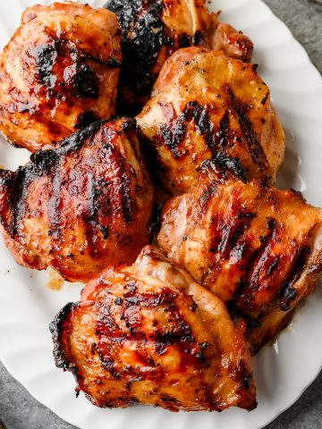 Serving platter piled with grilled maple Dijon chicken thighs.