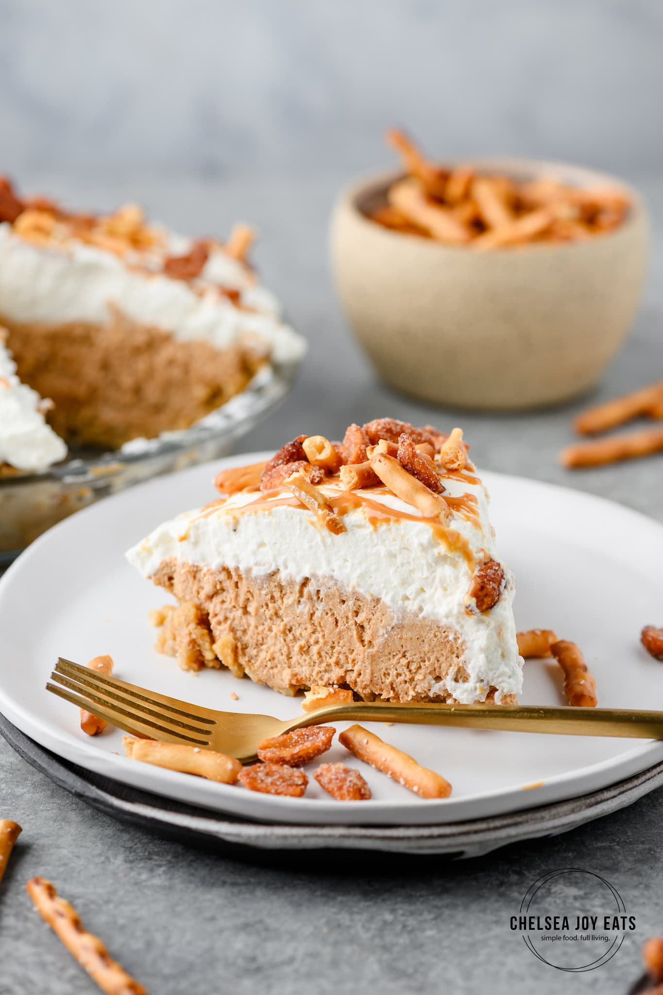 Slice of gluten free peanut butter pretzel pie topped with pretzels, peanuts, and peanut butter drizzle