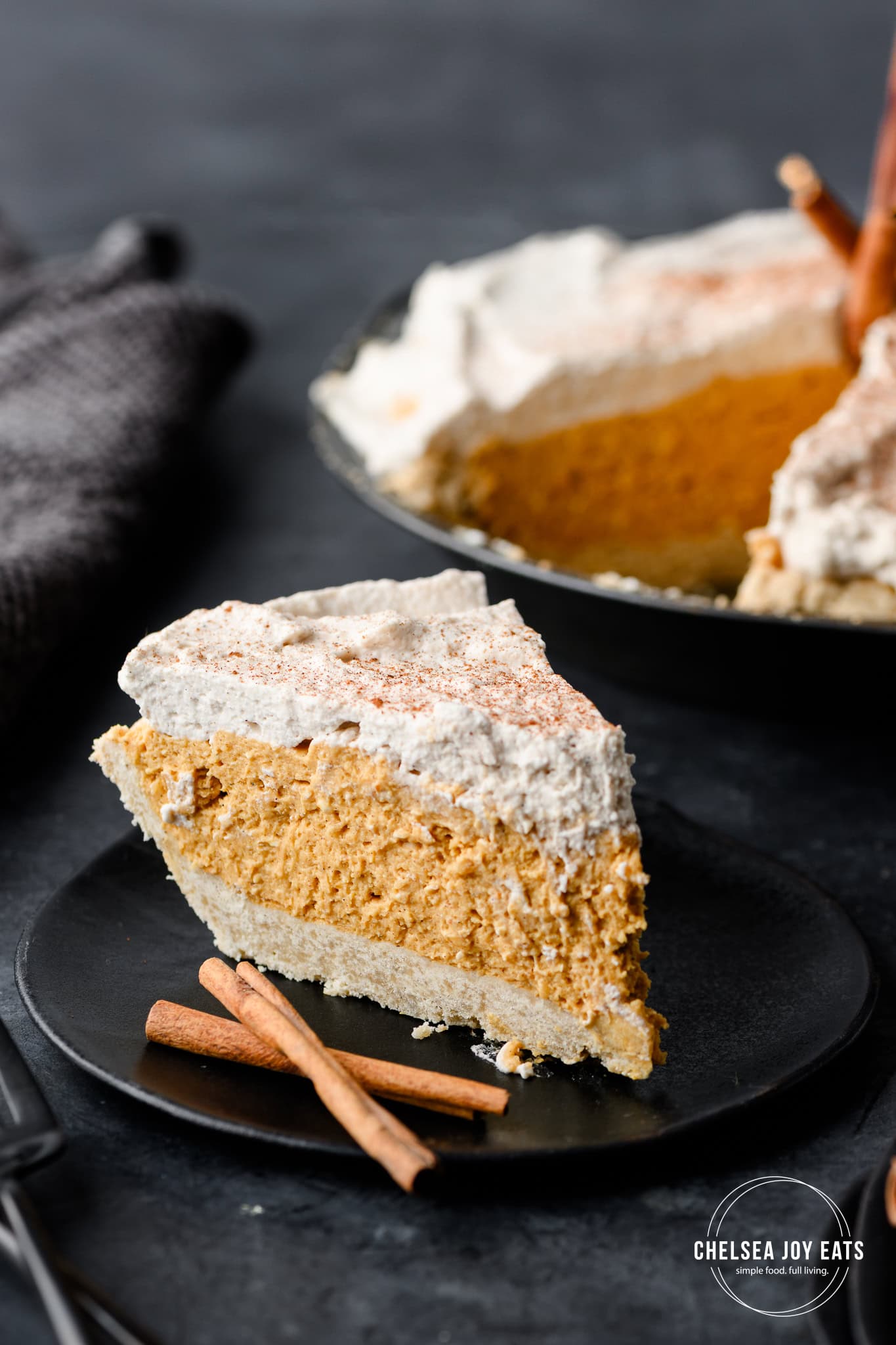 Closeup of a slice of no bake pumpkin pie on a plate with the rest of the pie in the background