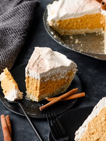 No bake pumpkin pie on a plate with a forkful taken out, with the rest of the pie in the background