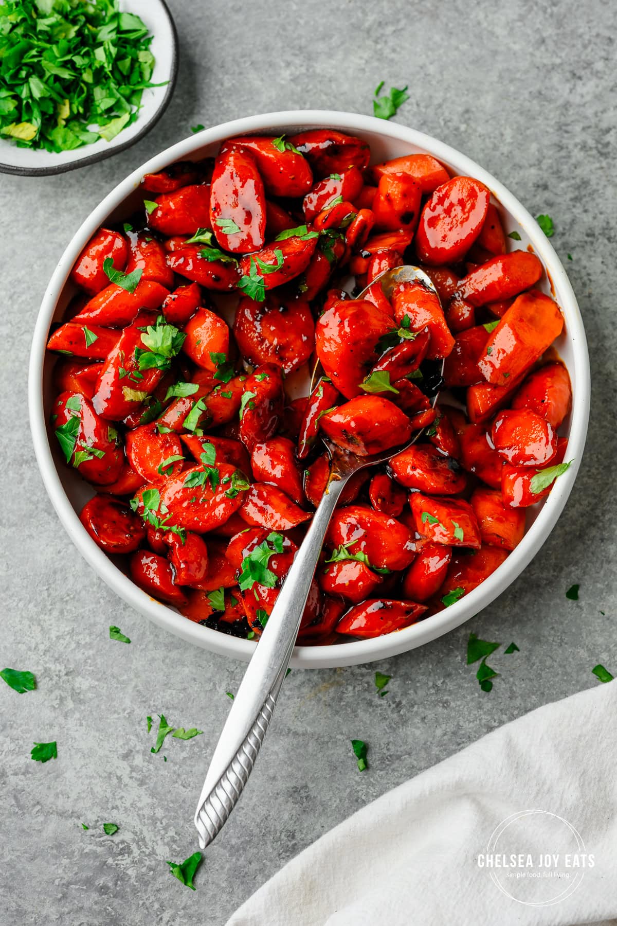 Serving bowl with hot honey carrots and garnished with parsley