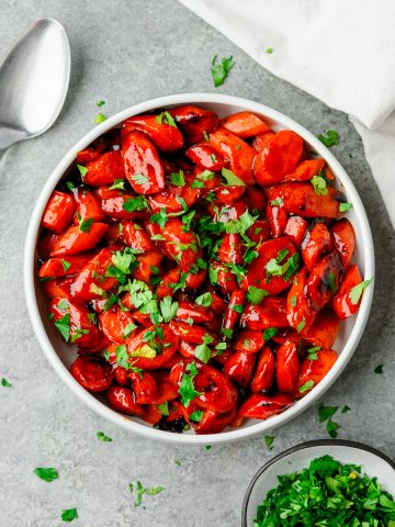 Bowl full of hot honey glazed carrots and garnished with parsley
