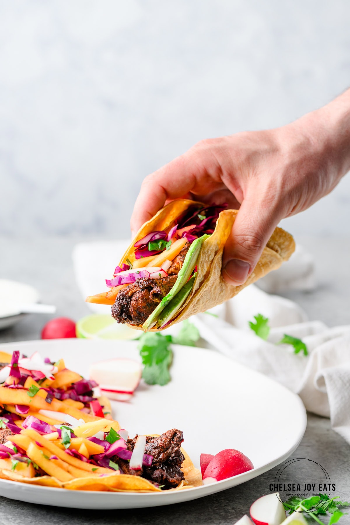 Person lifting an ancho chicken taco from a plate