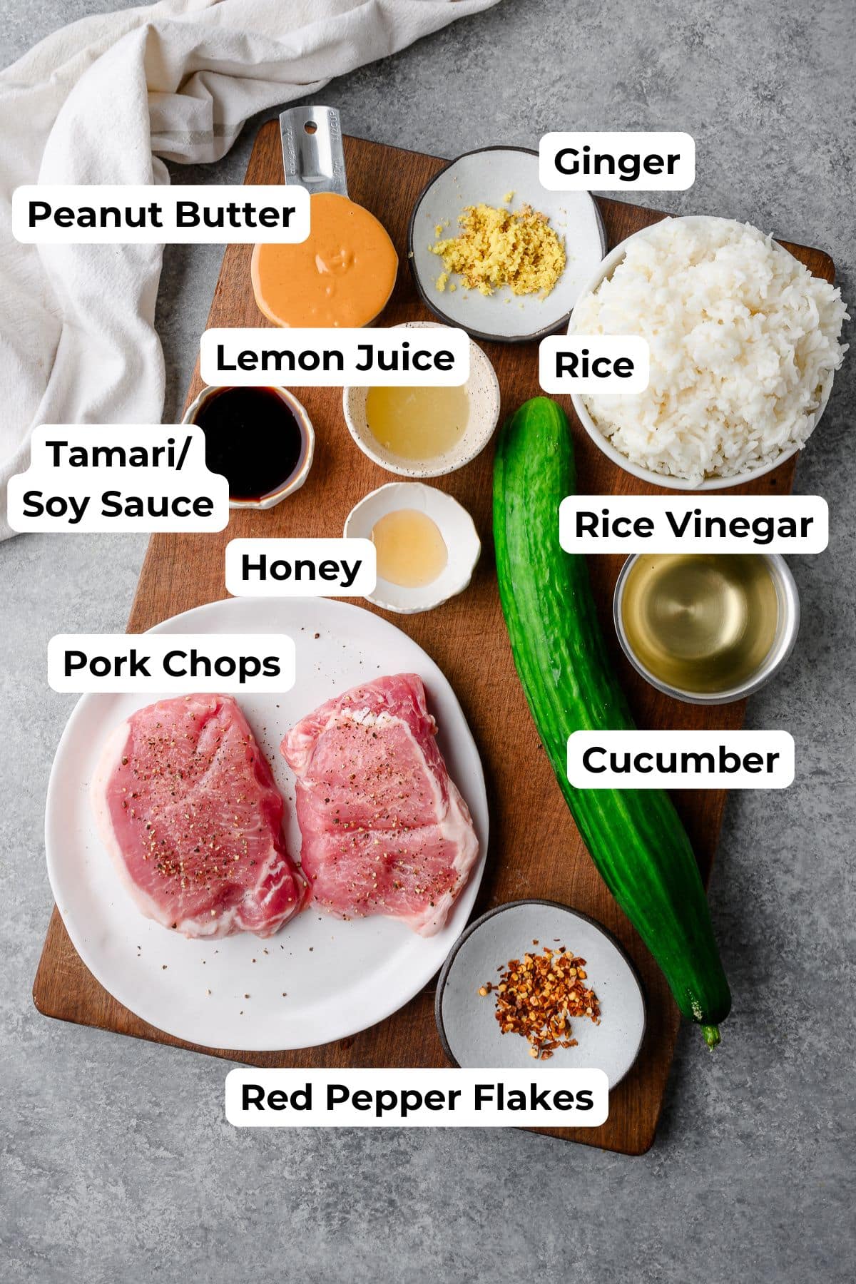 Ingredients for pork, rice, and cucumber bowls with peanut sauce, with labels on all ingredients.
