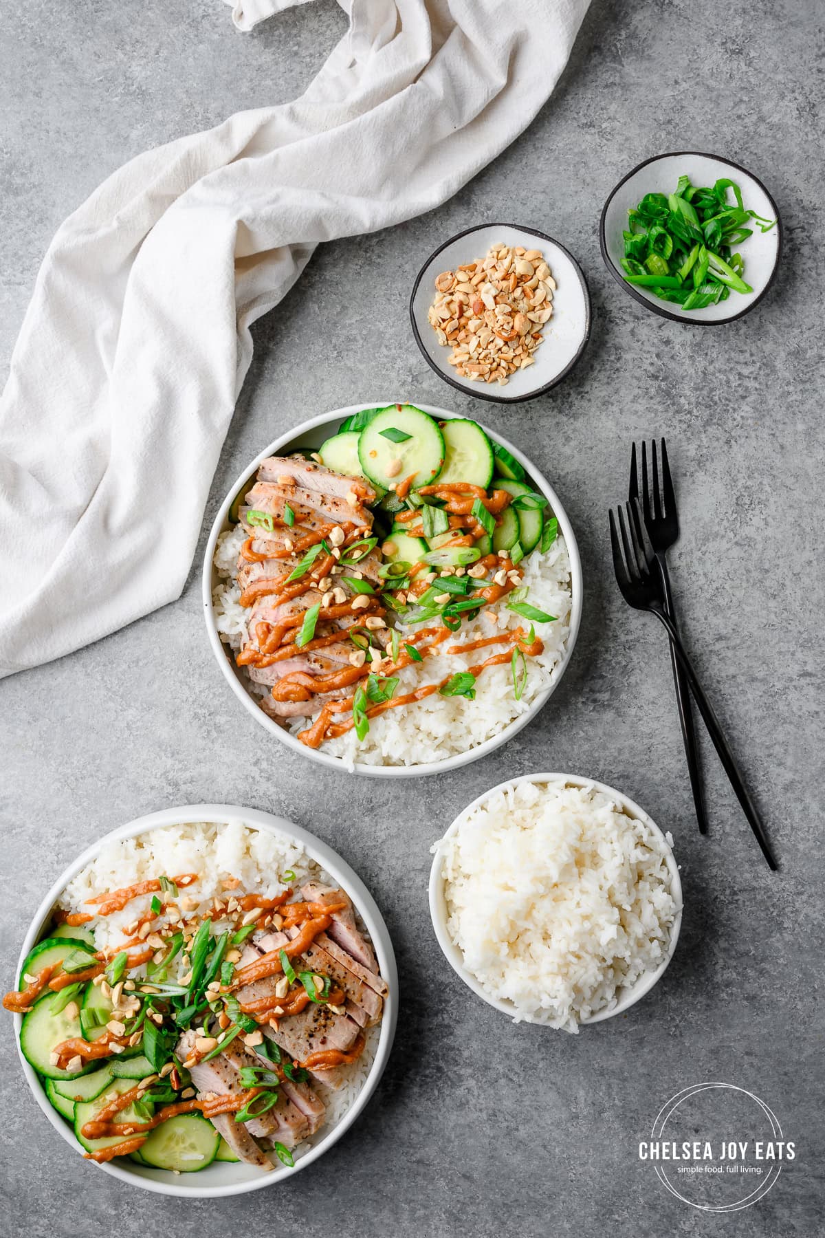 Assembled pork and rice bowls with peanut sauce, plus bowls of extra rice and garnish.