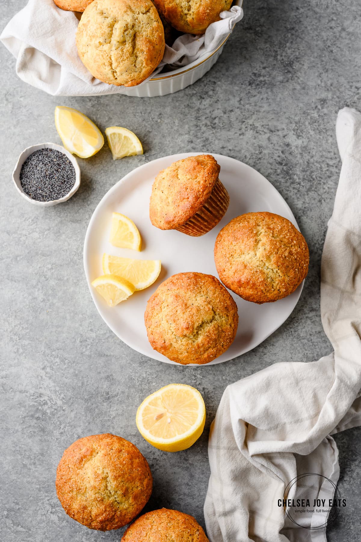 Overhead view of a plate with multiple lemon poppyseed muffins, garnished with lemon wedges