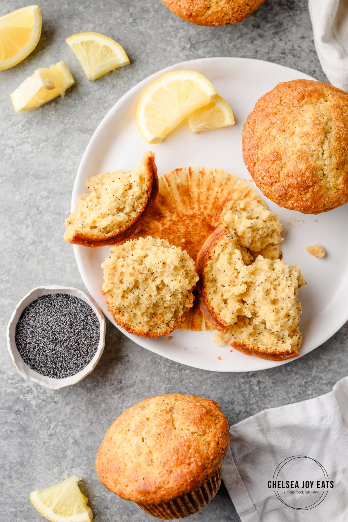 Plate with lemon poppyseed muffins, one that has been torn into and is in pieces