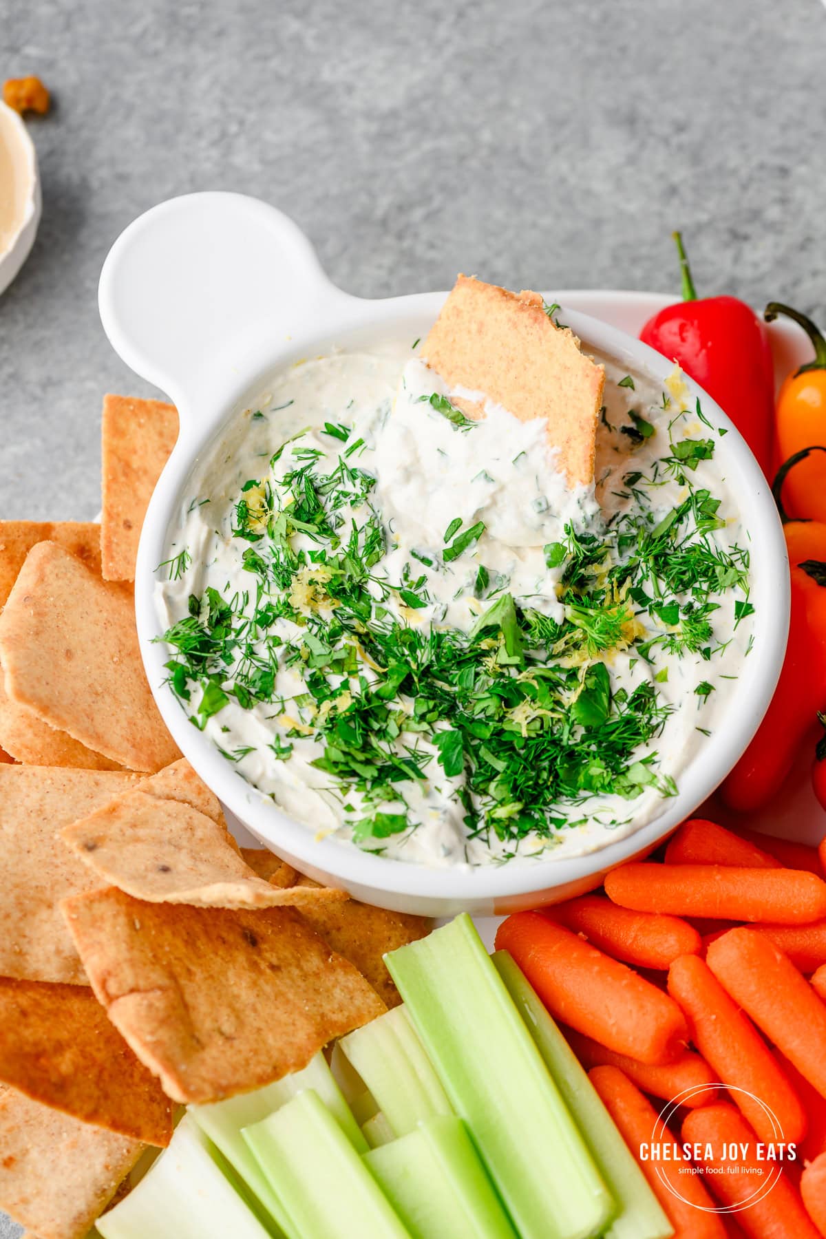 Overhead view of Lemon Herb Tahini Yogurt Dip with chips and vegetables surrounding the dish