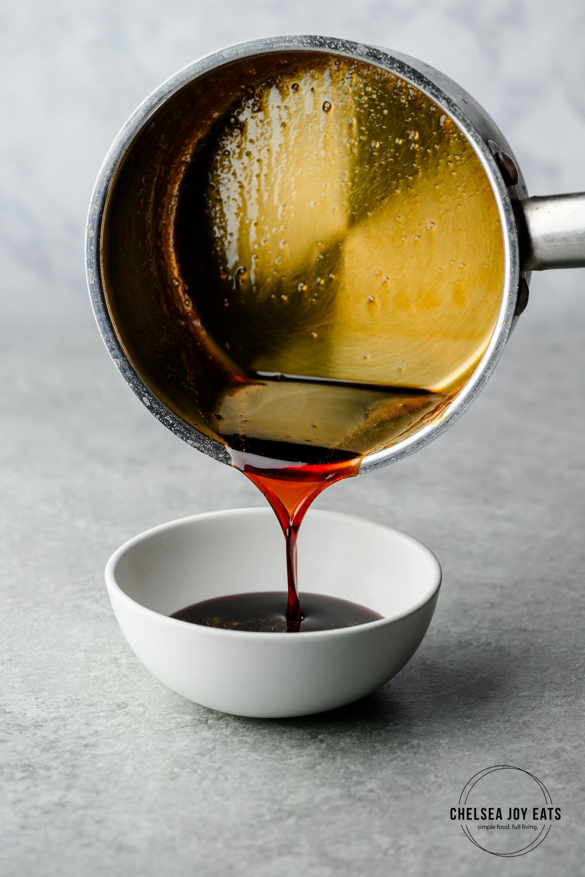 Homemade teryiaki sauce being poured from a saucepan into a small bowl