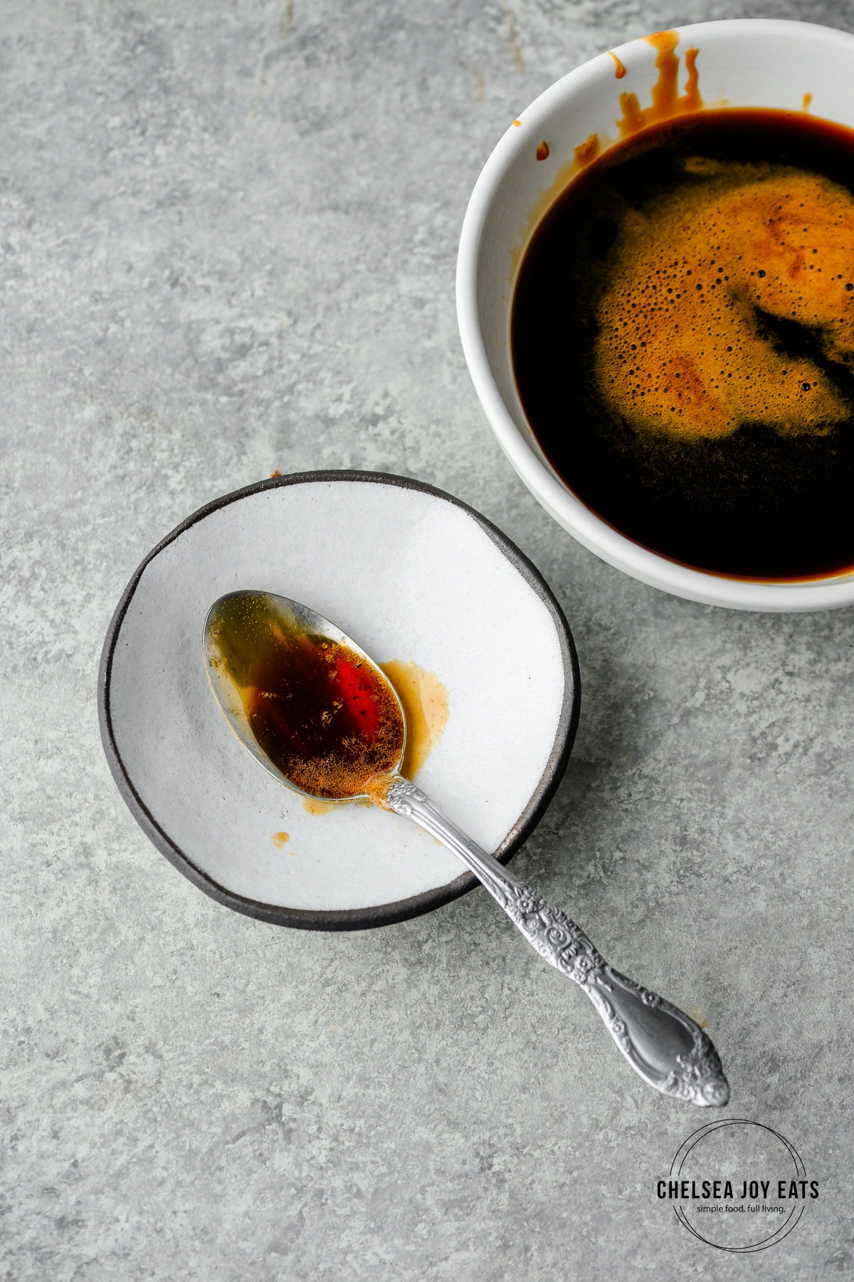 Spoon with homemade teriyaki sauce on a spoon rest with a bowl of teriyaki beside