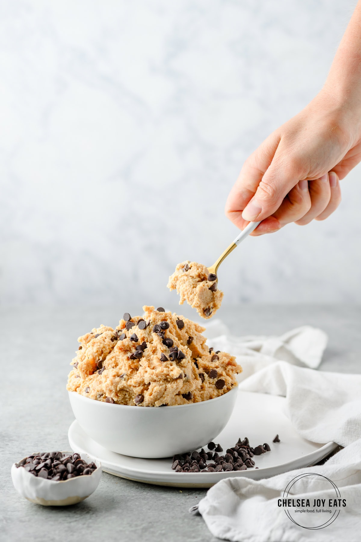 Person scooping a helping of chickpea cottage cheese cookie dough with a spoon