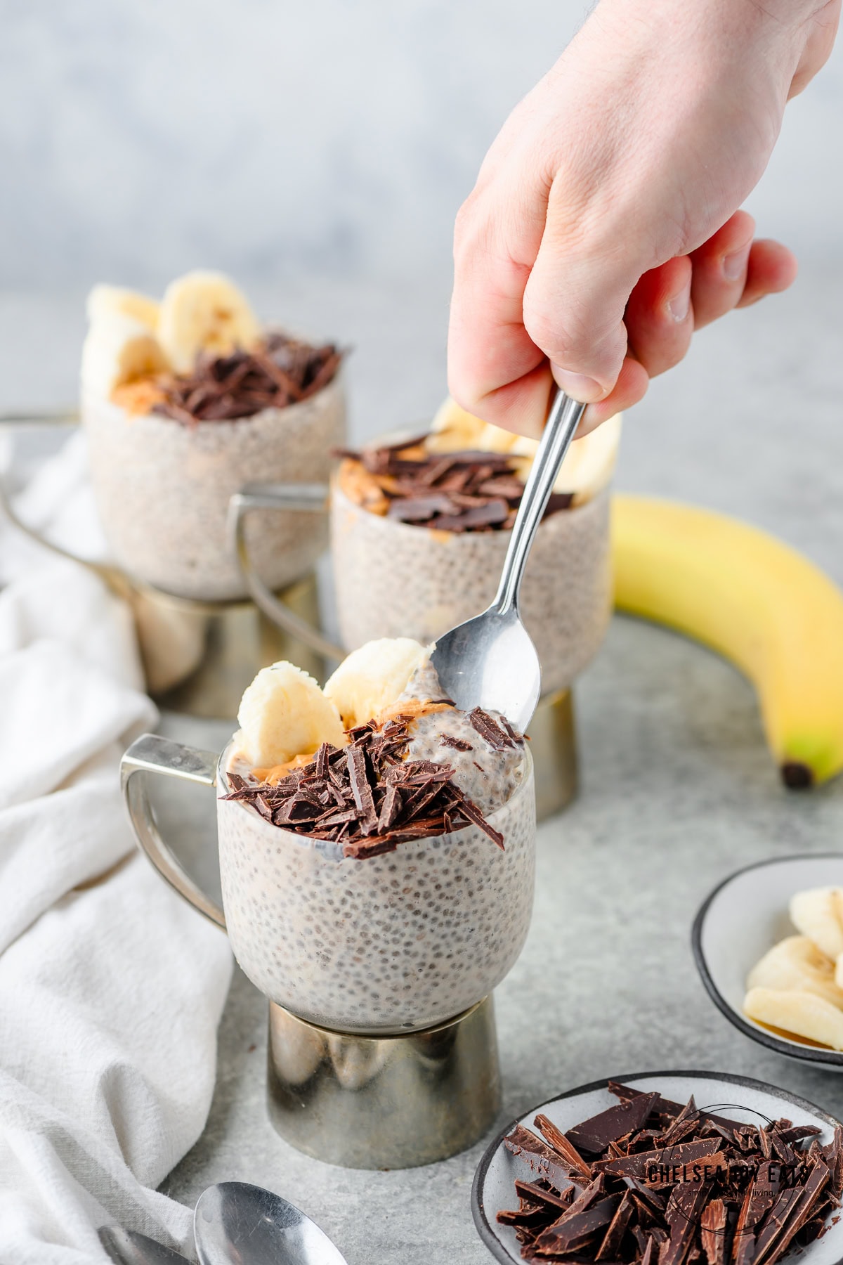 Person scooping a spoonful of peanut butter and banana chia pudding out of an individual serving jar