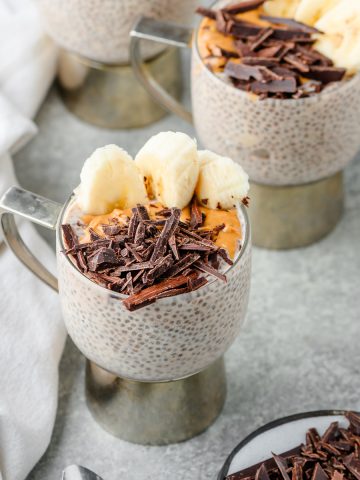 Chunky monkey chia pudding made with peanut butter powder and banana, topped with peanut butter, sliced banana, and chopped dark chocolate