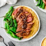 Overhead view of plate loaded with polenta, blistered shishitos, and sliced skirt steak with pan sauce