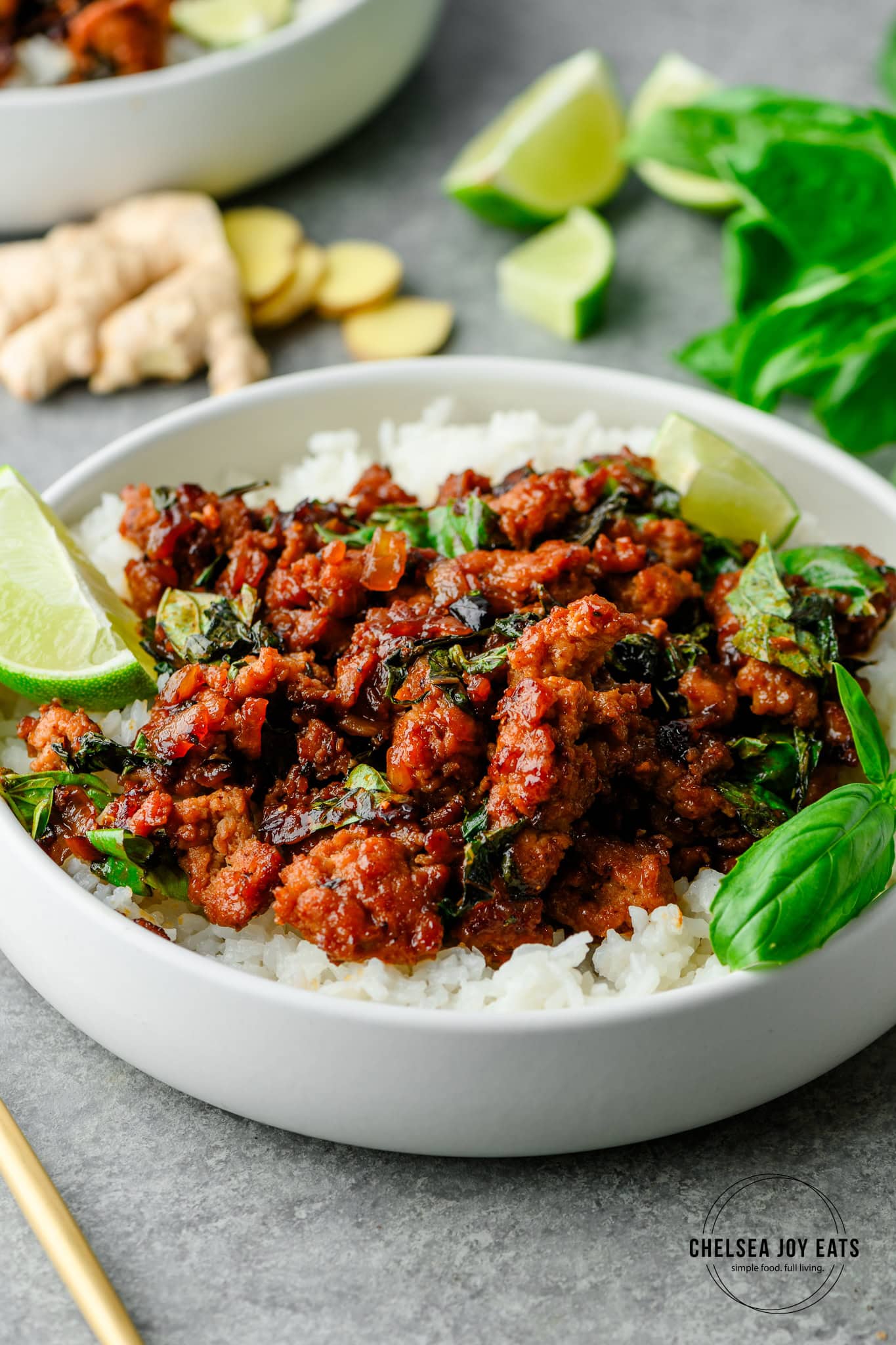Closeup of a serving of Thai basil turkey served over rice and garnished with lime and fresh basil leaves