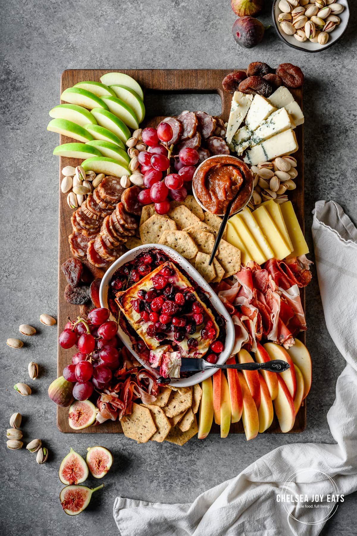 Fall-inspired charcuterie board with seasonal produce like apples, pears, and cranberries