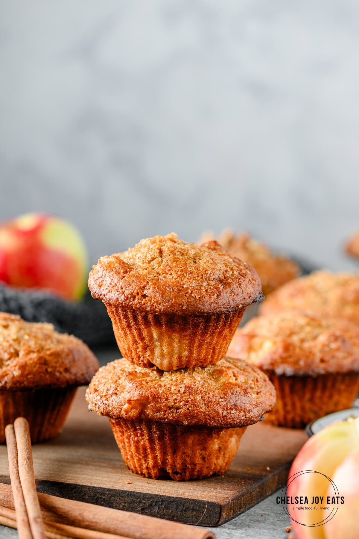 Two apple muffins stacked on top of one another, with more muffins in the background