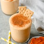 Closeup of a pumpkin smoothie dusted with pumpkin pie spice and garnished with graham crackers