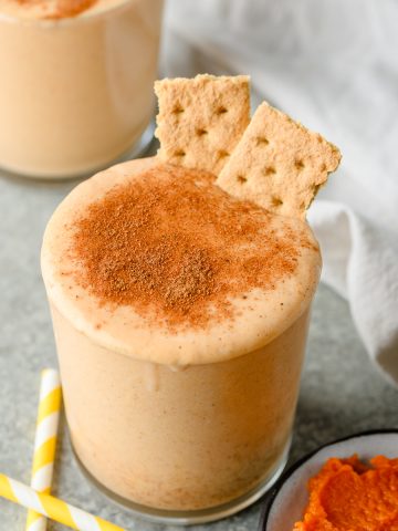 Closeup of a pumpkin smoothie dusted with pumpkin pie spice and garnished with graham crackers