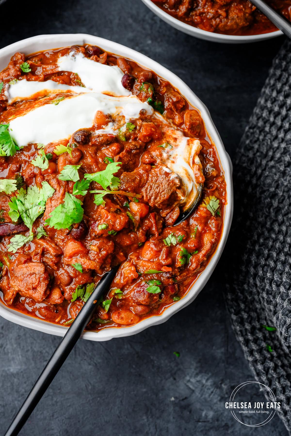 Closeup of a spoon scooping steak chili from a bowl