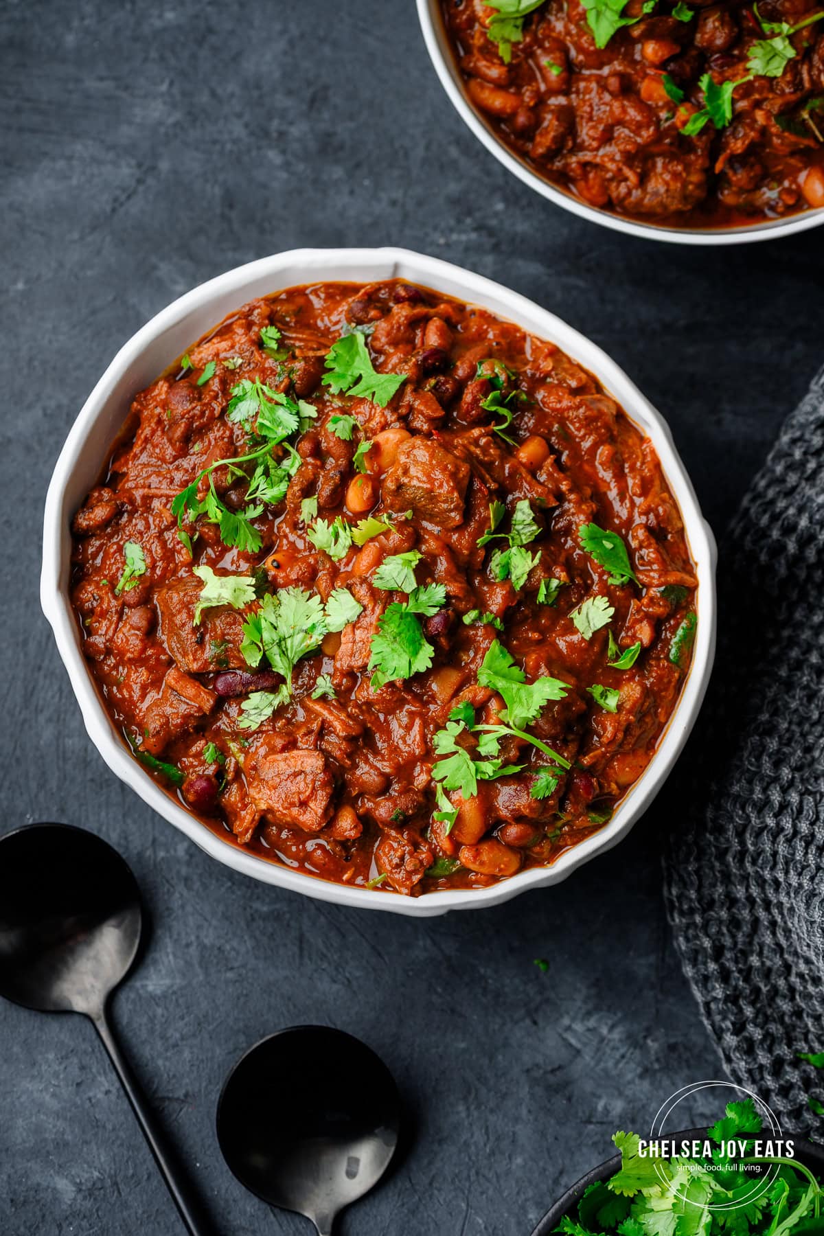 Bowl filled with hearty chipotle chili made with flank steak, topped with minced fresh cilantro