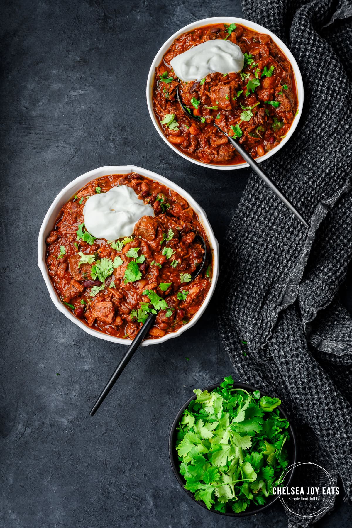 Overhead view of bowls willed with chipotle flank steak chili topped with fresh cilantro and a dollop of sour cream