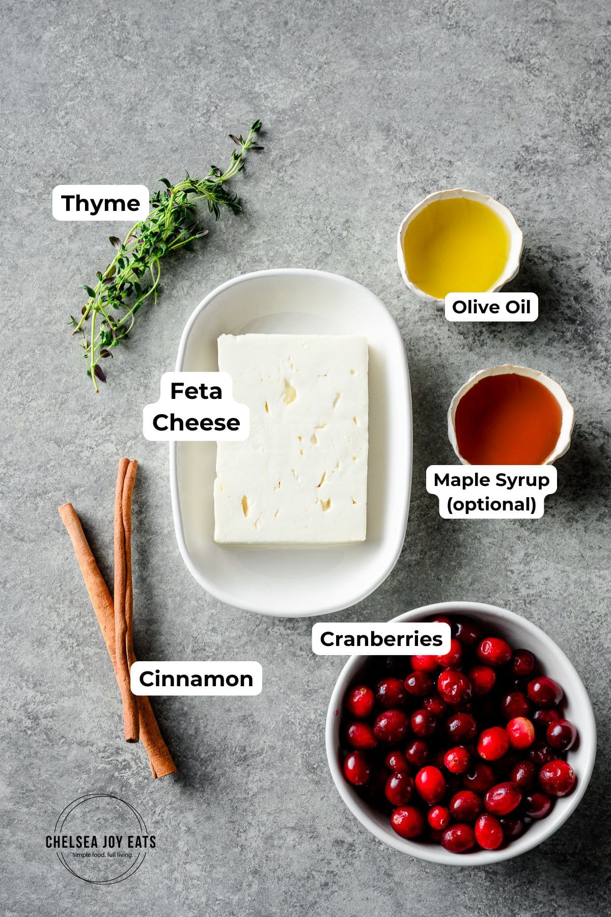 Ingredients for a baked feta cheese with cranberries recipe, with text labels for each ingredient