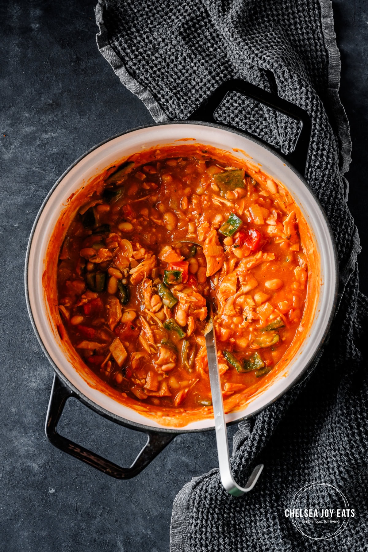 Dutch oven with turkey and pumpkin chili, with a ladle ready to scoop