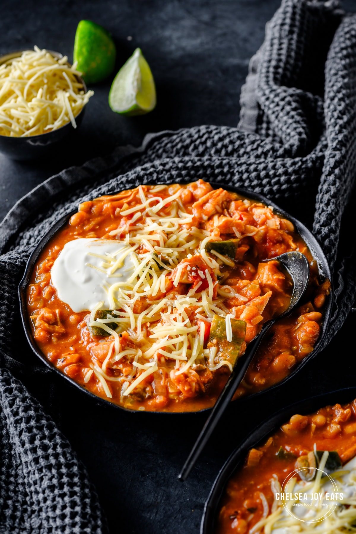 Bowl with leftover turkey and pumpkin chili garnished with cheddar cheese and sour cream