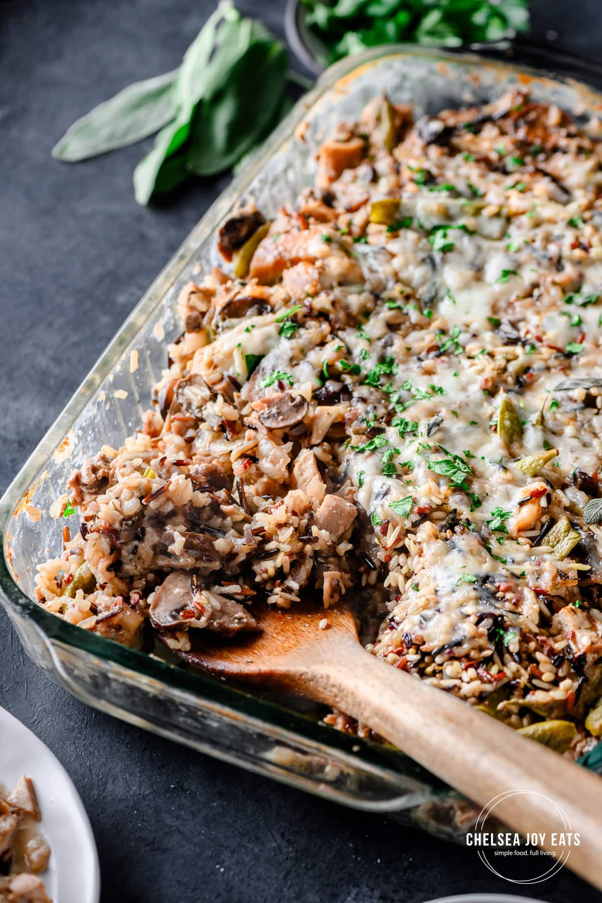 Closeup of a spoon scooping turkey and wild rice casserole out of a dish