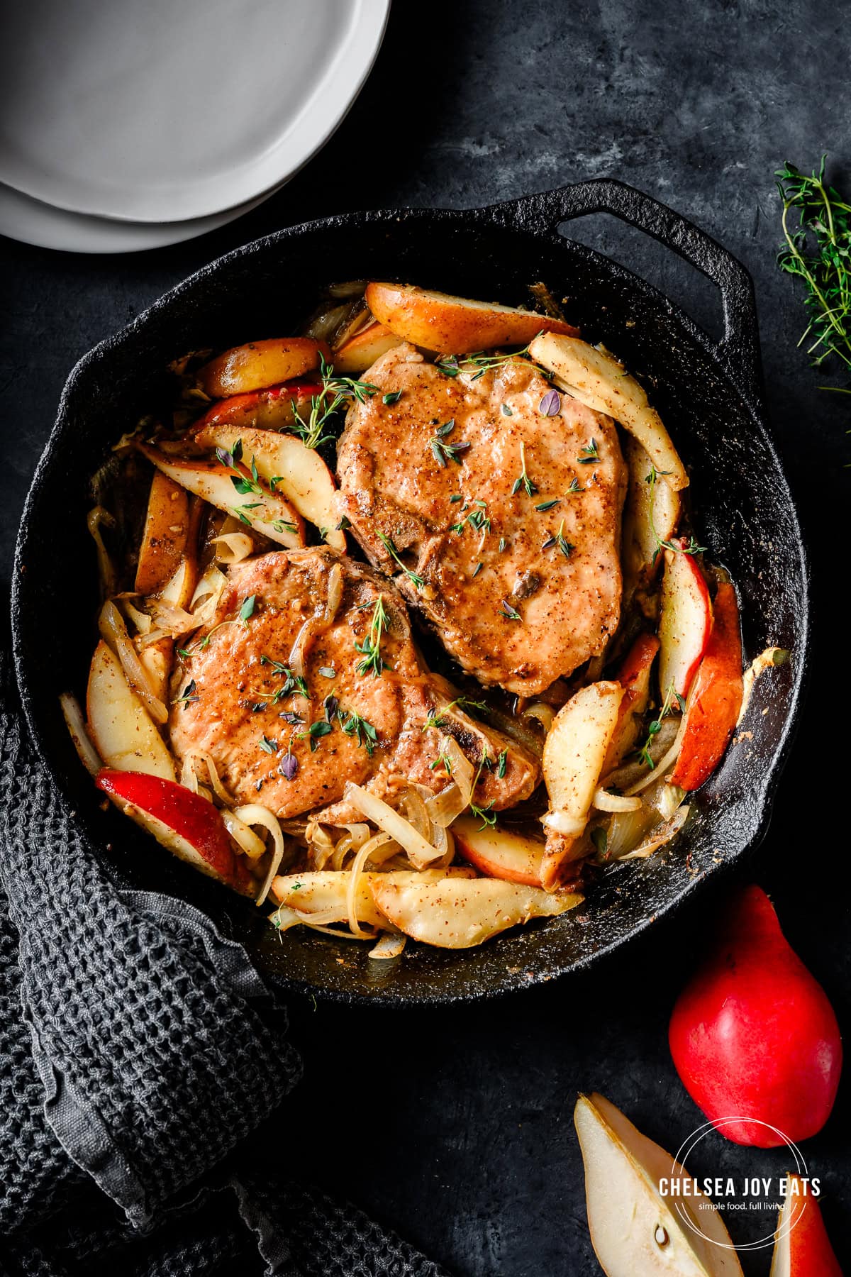 Overhead view of a cast iron skillet with cooked bone-in pork chops with maple glazed sliced pears