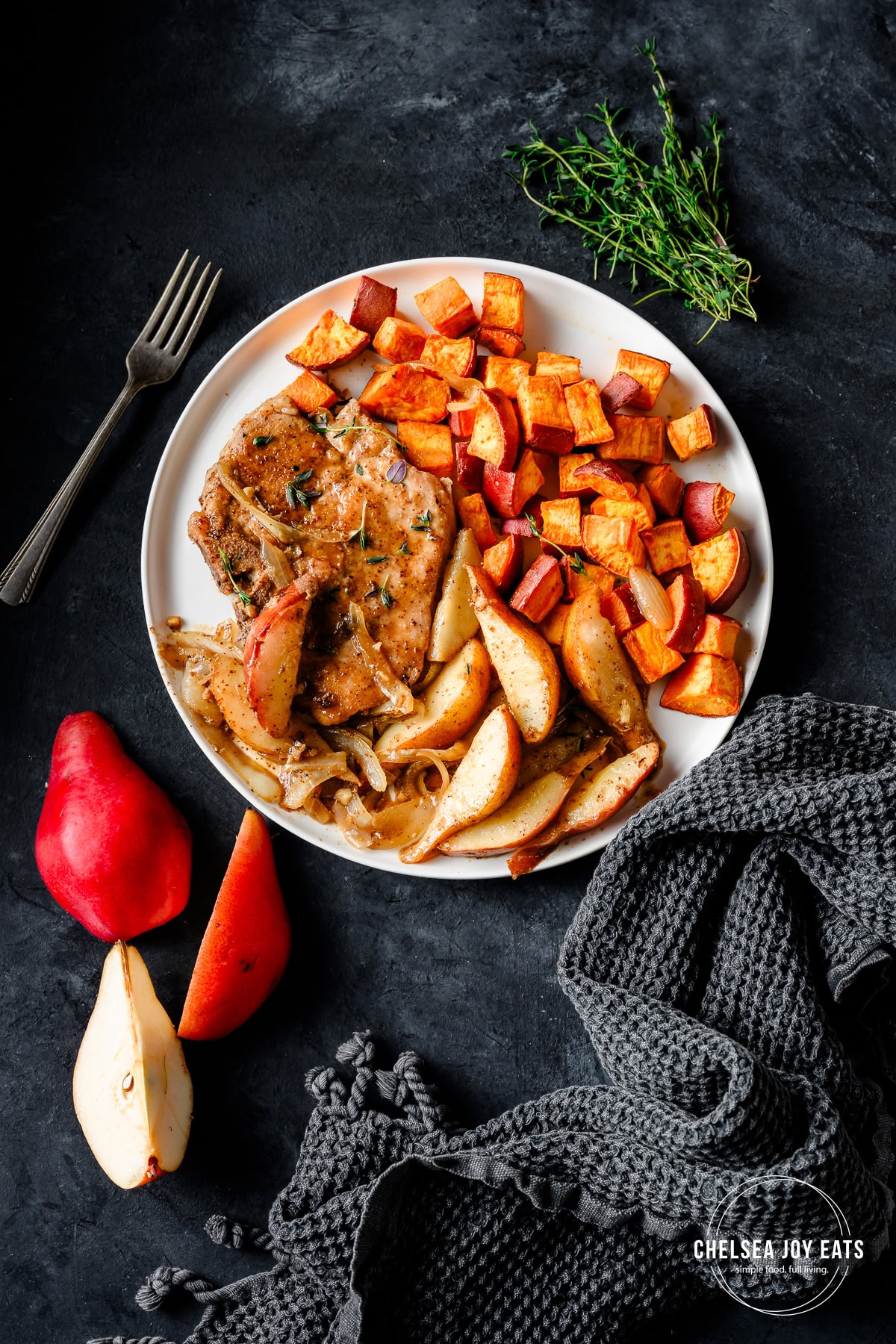 Pork chop served on a plate with maple glazed pears and roasted sweet potatoes