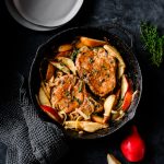 Cast iron skillet with bone-in pork chops and sauteed pears
