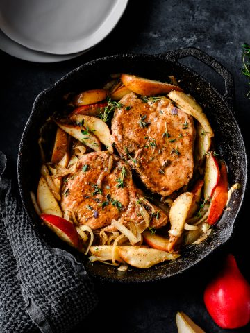 Cast iron skillet with bone-in pork chops and sauteed pears