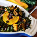 Closeup of Warm Winter Kale Salad with delicata squash and hazelnuts in a casserole dish