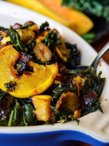 Closeup of Warm Winter Kale Salad with delicata squash and hazelnuts in a casserole dish
