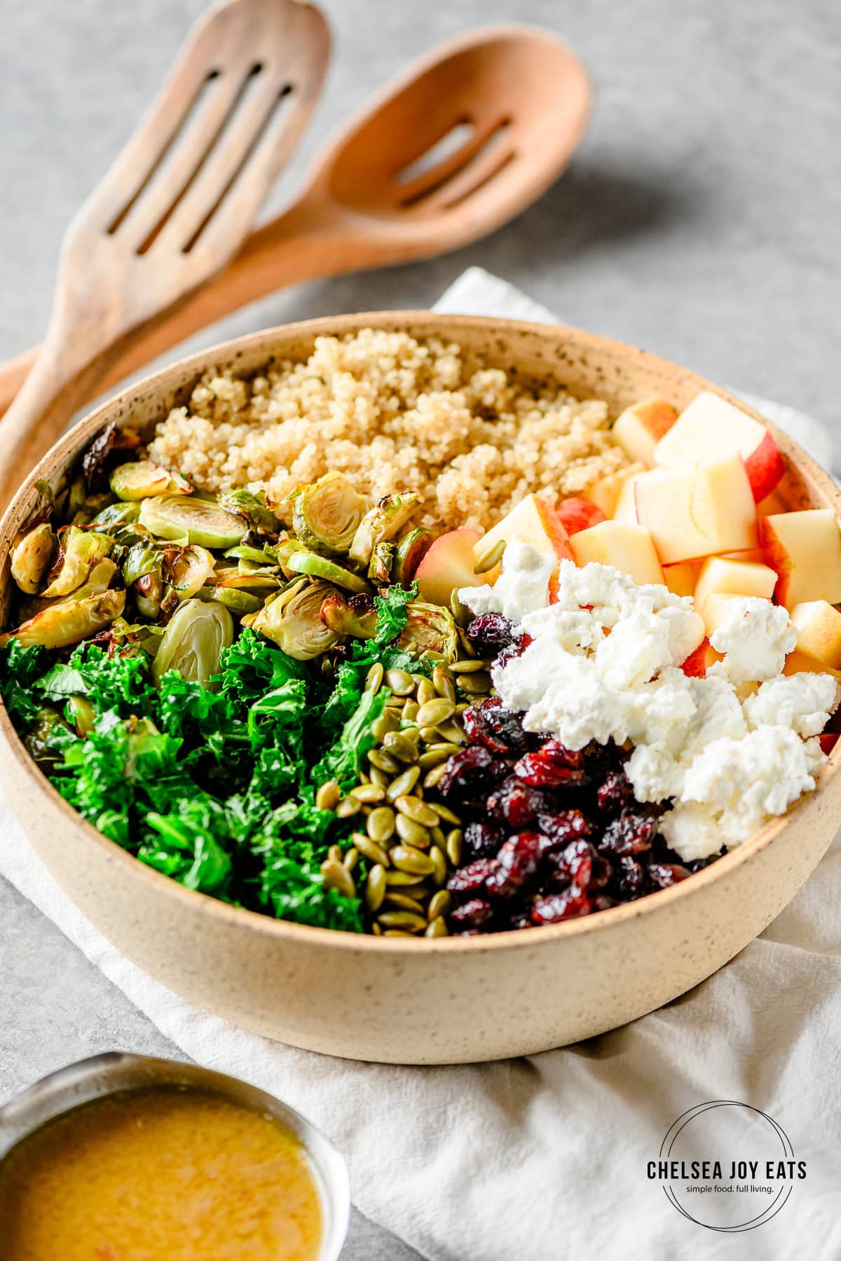 Bowl with ingredients for a roasted brussels sprout salad with quinoa, kale, apples, and an apple dressing