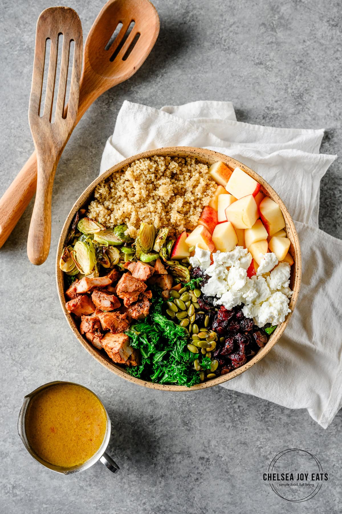 Overhead view of ingredients for a quinoa and brussels sprouts salad arranged in a bowl before tossing with dressing