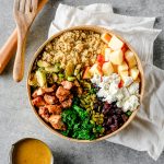 Overhead view of a roasted brussels sprout salad with quinoa and kale divided by ingredients in a bowl
