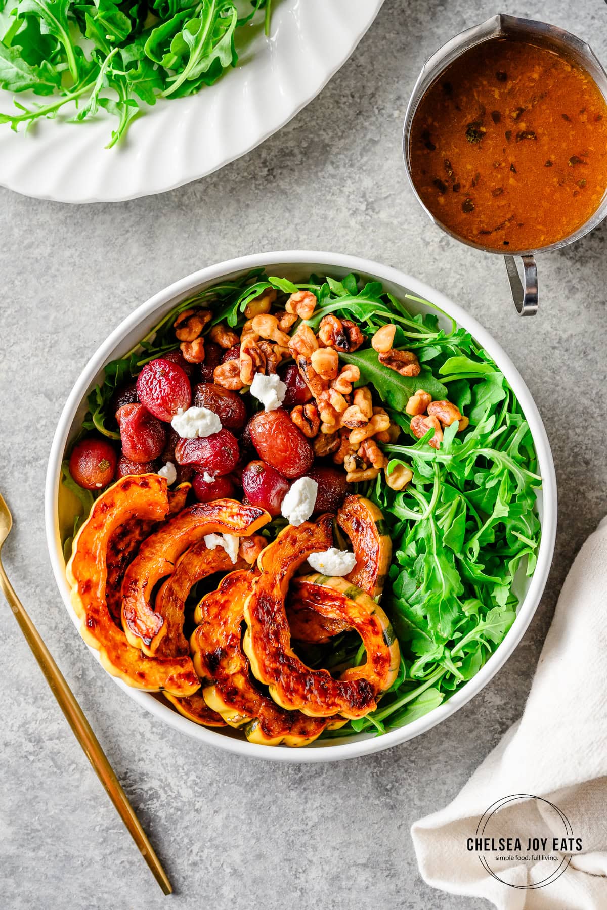 Bowl with arugula, roasted delicata squash, roasted grapes, toasted walnuts, and an orange dressing