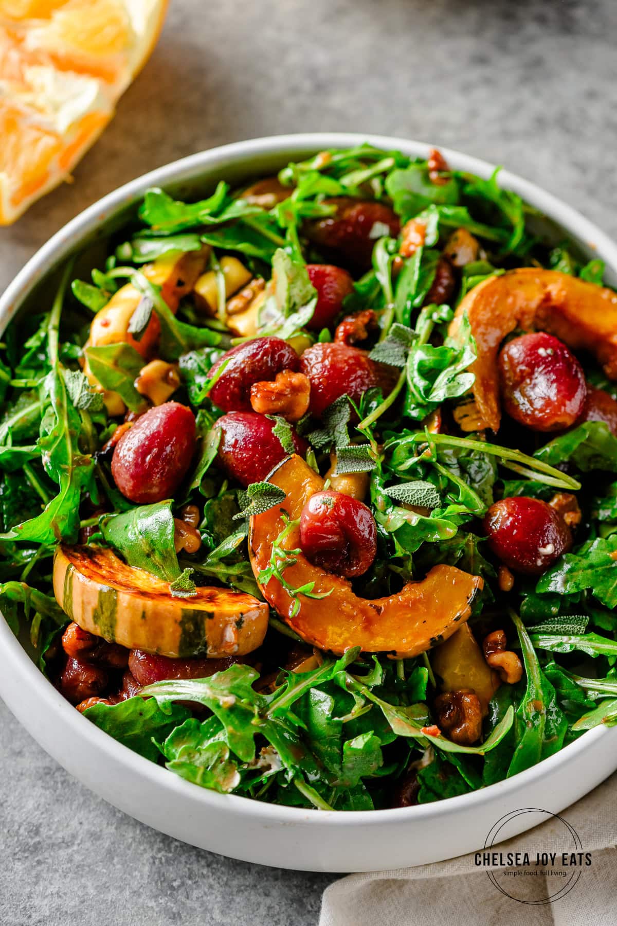 Bowl of arugula salad with roasted grapes and delicata squash