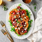 Overhead view of a roasted grape salad with delicata squash and arugula