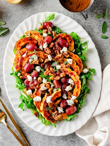 Overhead view of a roasted grape salad with delicata squash and arugula