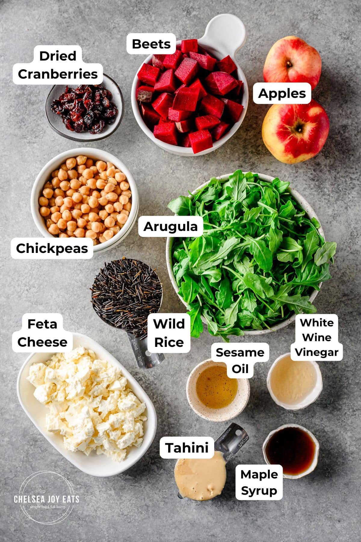 Ingredients for wild rice and arugula salad with maple tahini dressing, with text labels for each ingredient