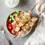 Overhead view of chicken souvlaki bowls with chicken skewers, rice, and fresh veggies