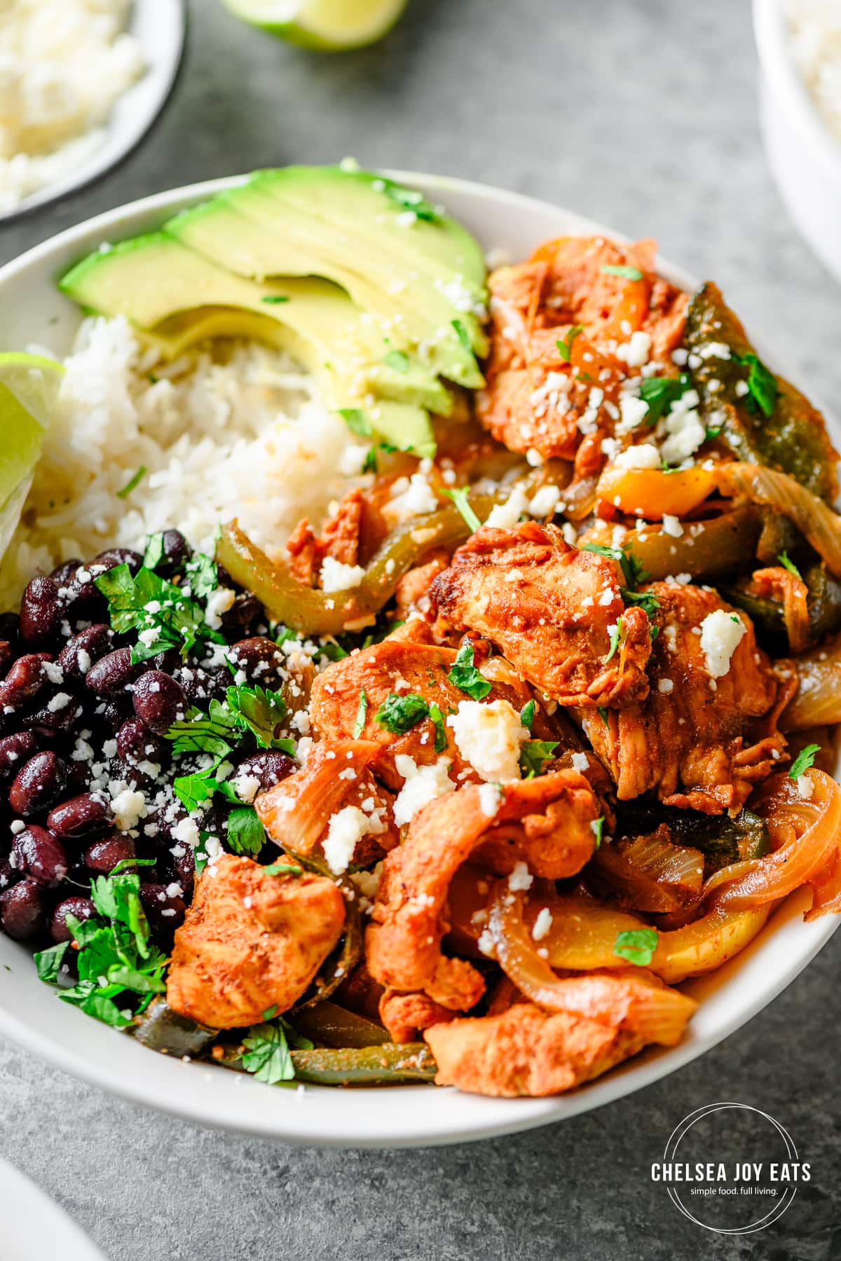 Closeup of fajita chicken bowls with bell peppers, onions, rice, beans, and avocado