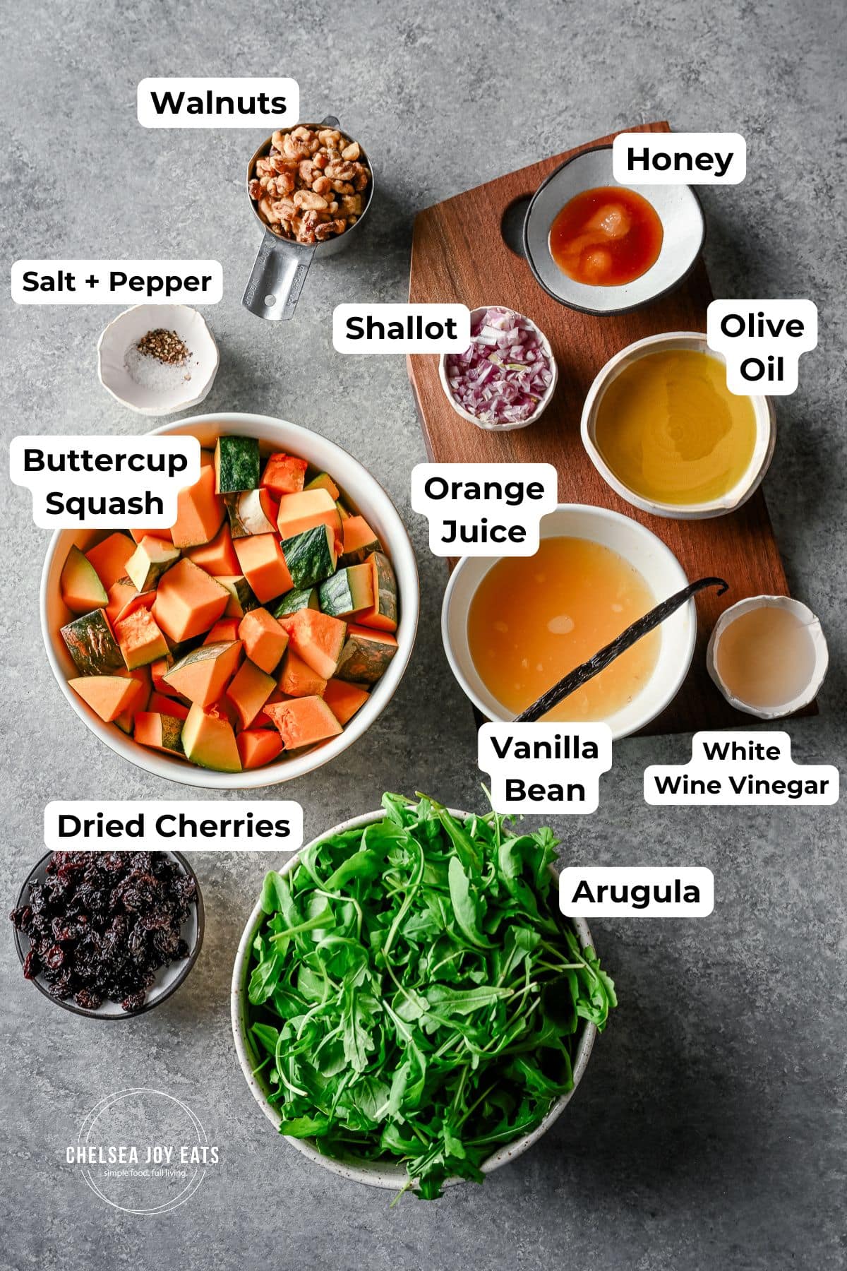 A variety of chopped butternut squash, arugula, dried cherries, and seasonings for cooking or salad.
