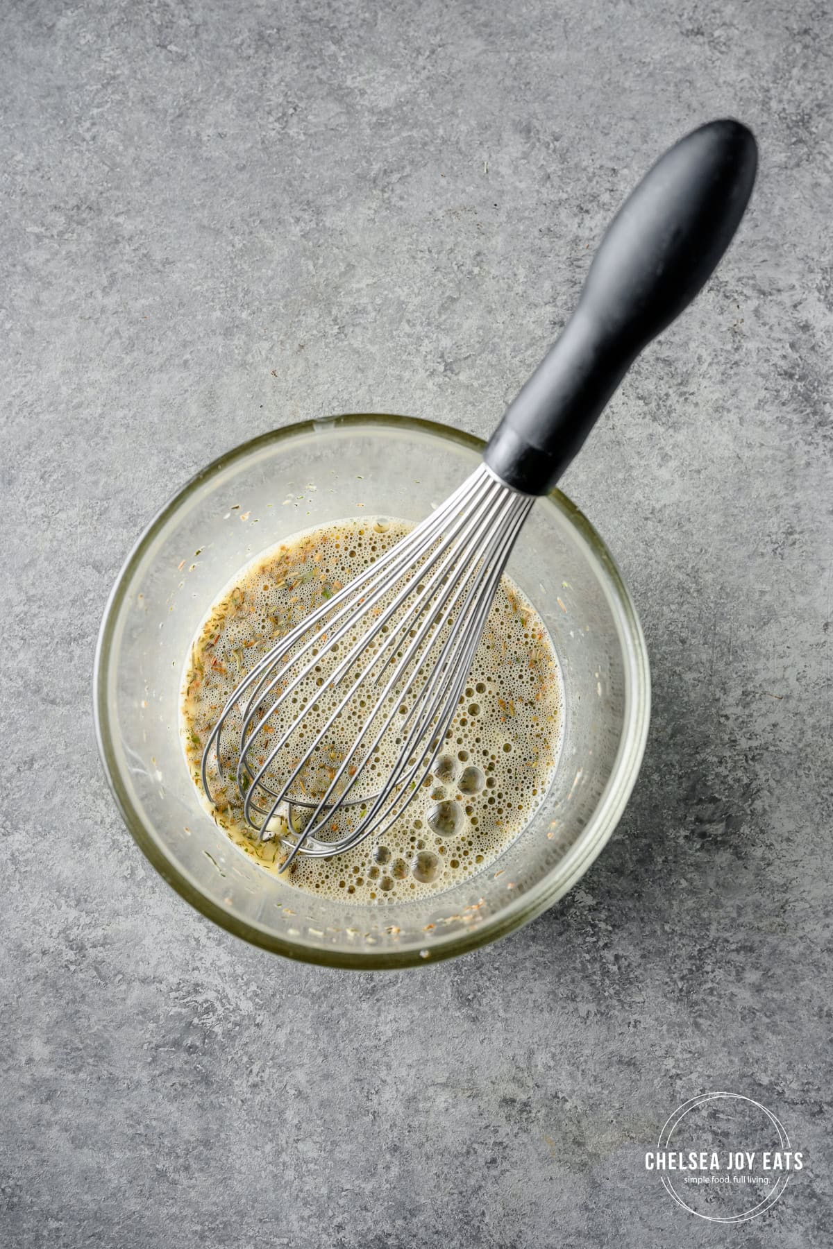 A bowl of whisked eggs and Greek seasoning