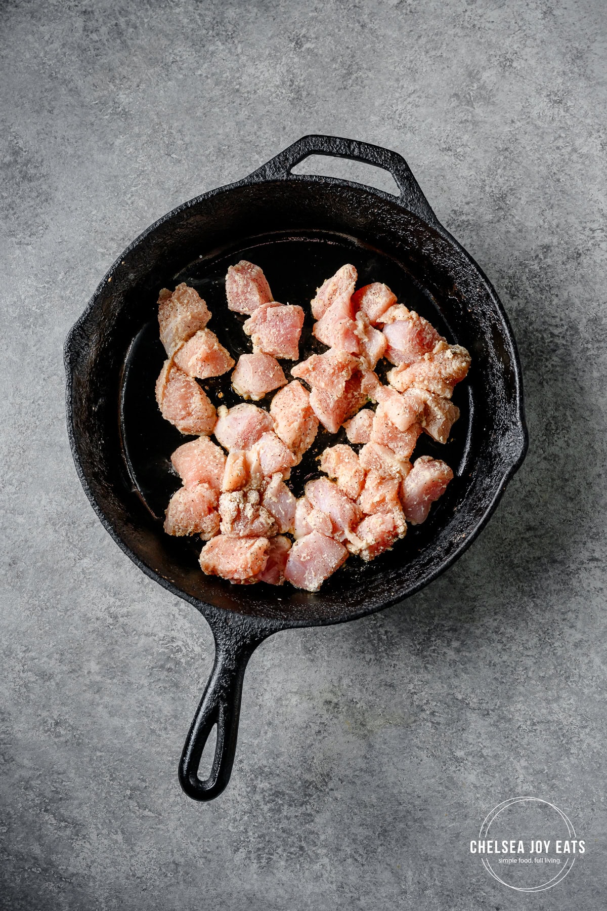 Floured chicken pieces cooking in a skillet